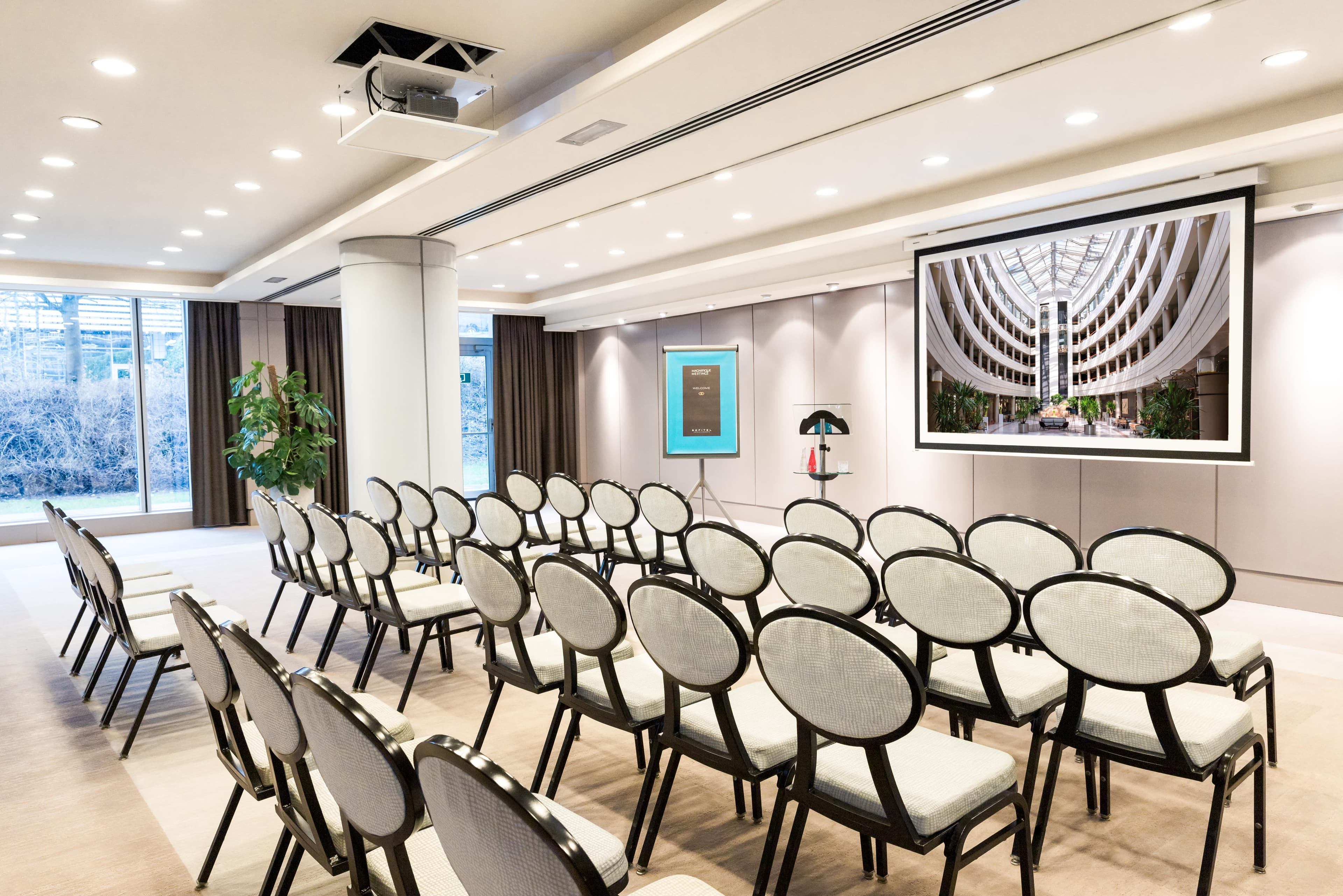 Conference room with rows of chairs and a projection screen, Sofitel Luxembourg.