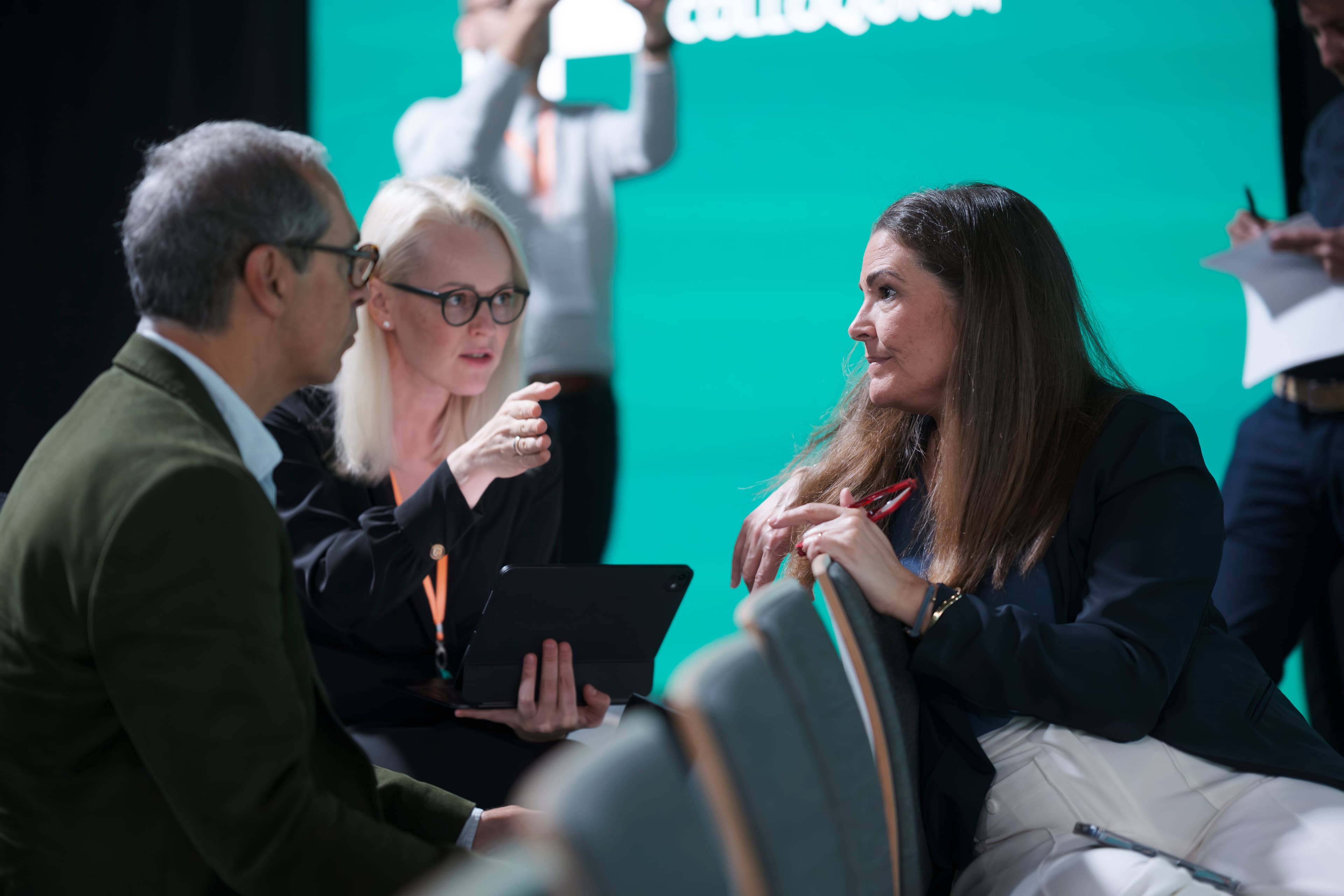 Three delegates in a focused discussion seated in armchairs at the SPX Colloquium