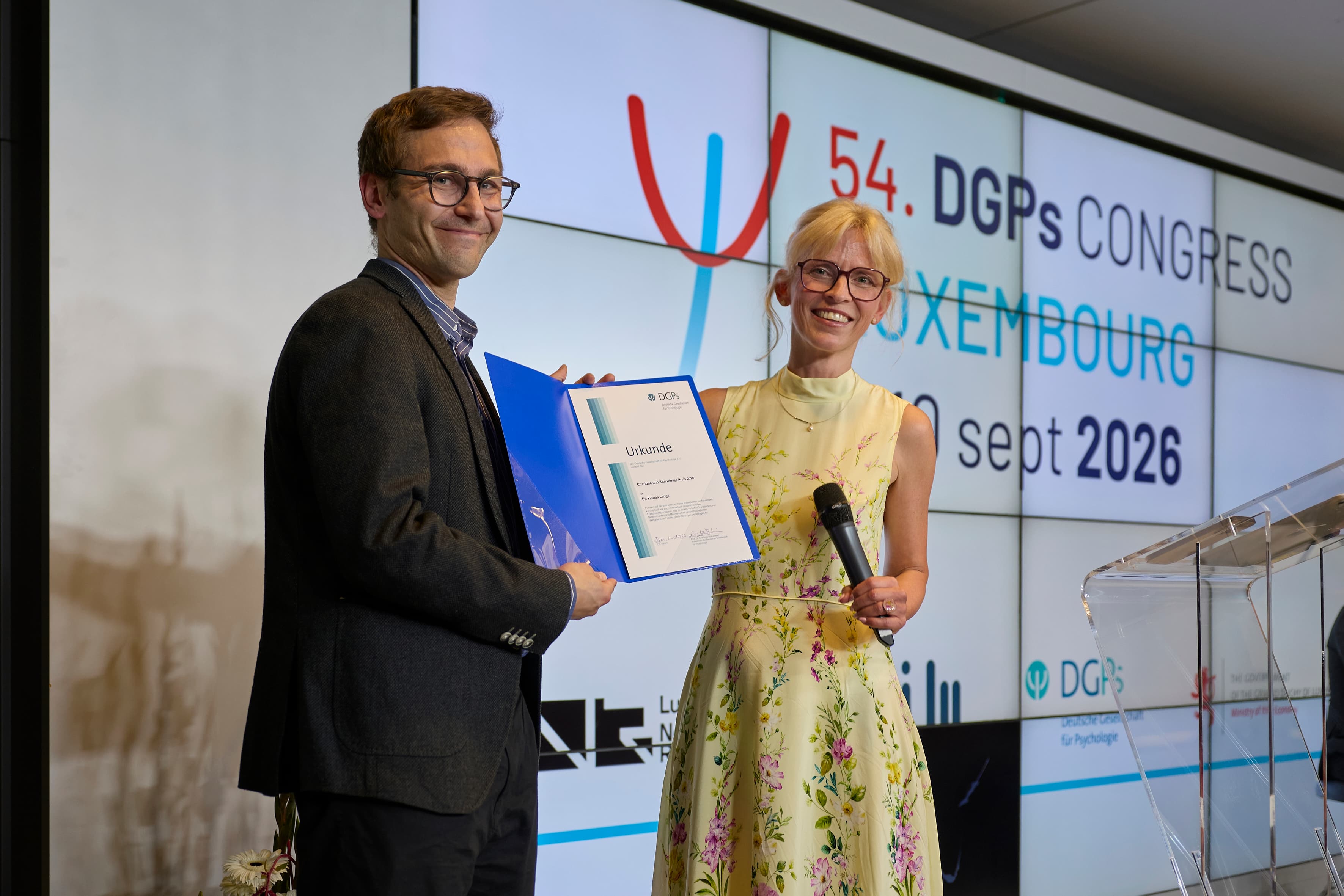 Representatives and organisers of the DGPs Congress pose together in front of research and institutional banners during the event in Luxembourg.