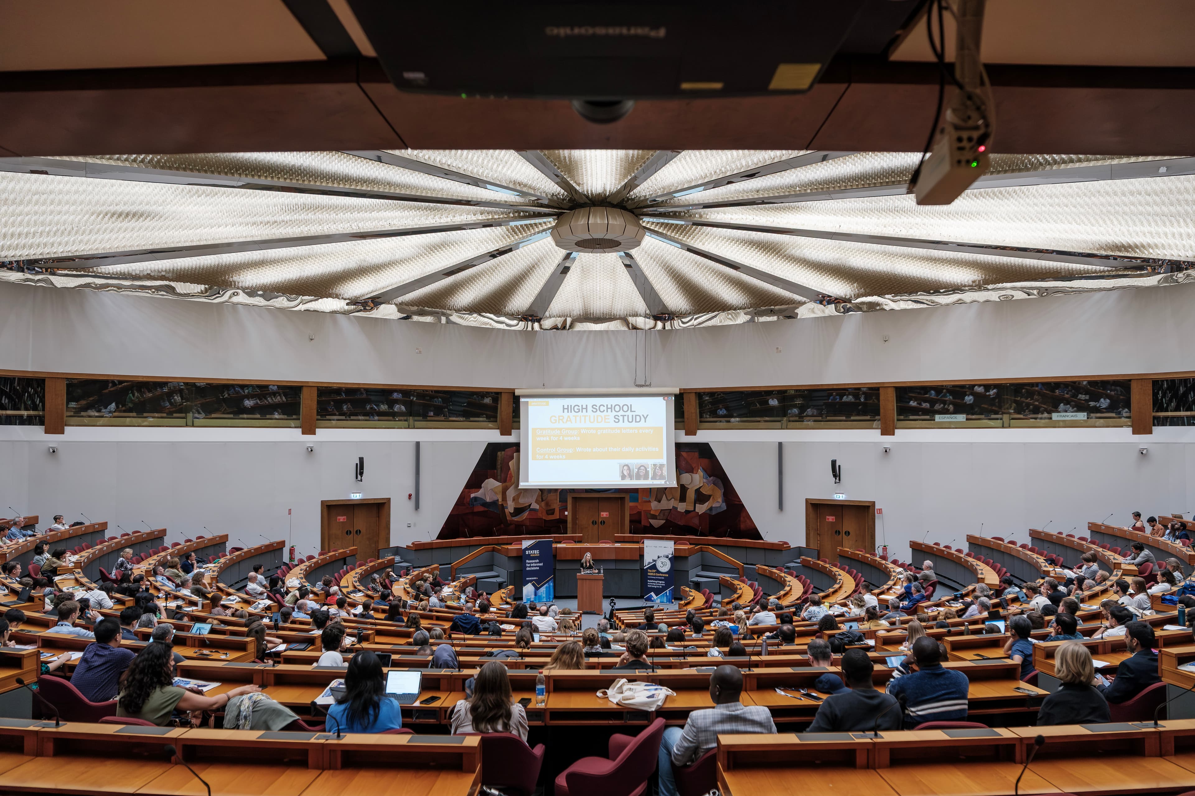 Delegates fill the round ECCL hemicycle under its sunburst ceiling during the ISQOLS conference