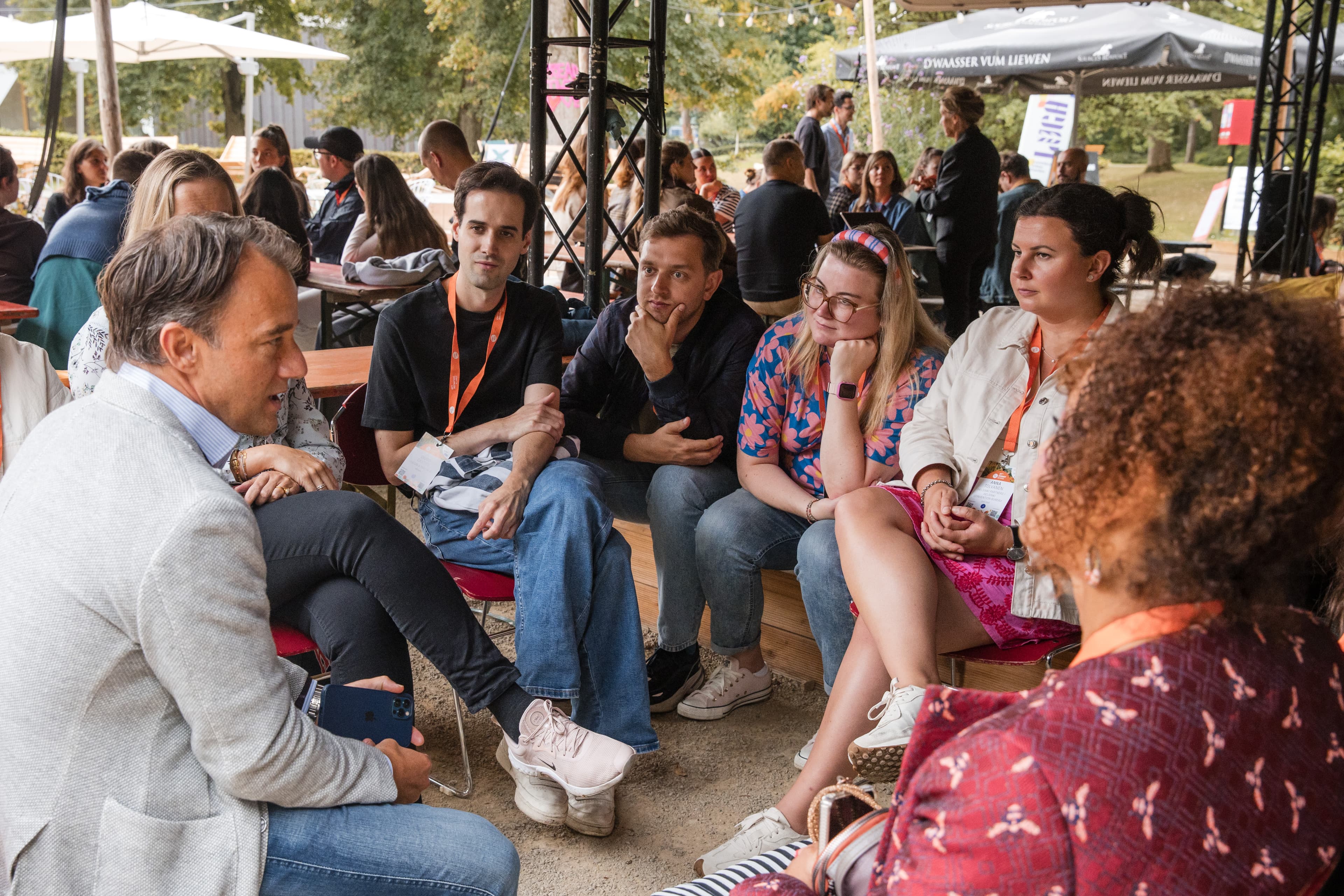 Young professionals in a group discussion at an outdoor garden networking event